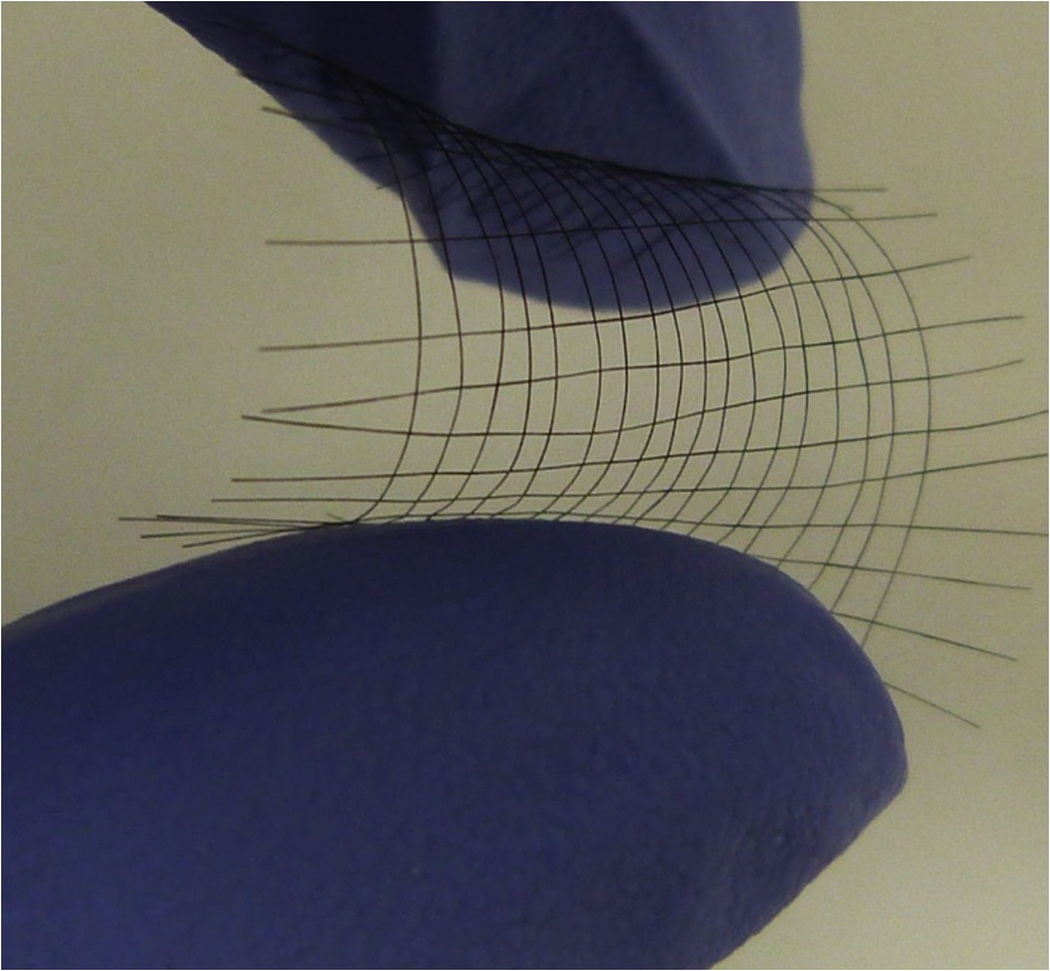 Rice University graduate student Changsheng Xiang holds a weave of carbon fibers created from graphene oxide flakes. (Credit: Tour Group/Rice University)